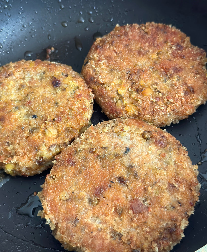 golden crispy vegan burgers bubbling away on the fry pan