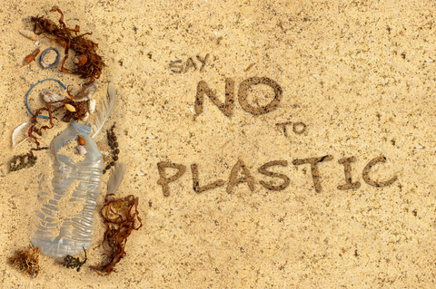 a used plastic bottle in the sand with the words "say no to plastic"