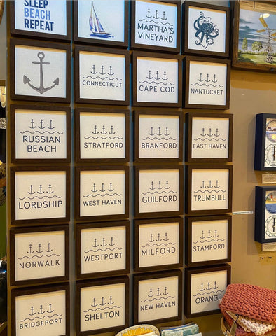 photograph of many signs with town names and anchor prints available for purchase in the store.