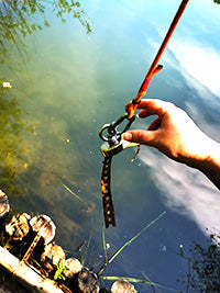 Neodymium fishing magnet hold piece of rusty metal over lake.