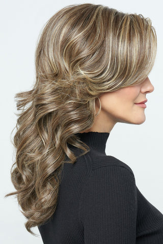 Women looking to the side as she is wearing a beautifully wavy wig with long layered bangs.