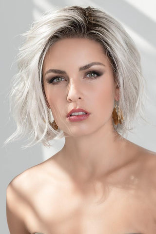 Esprit wig styled to the side, worn on an elegant looking women in the color Silver Blonde Rooted.