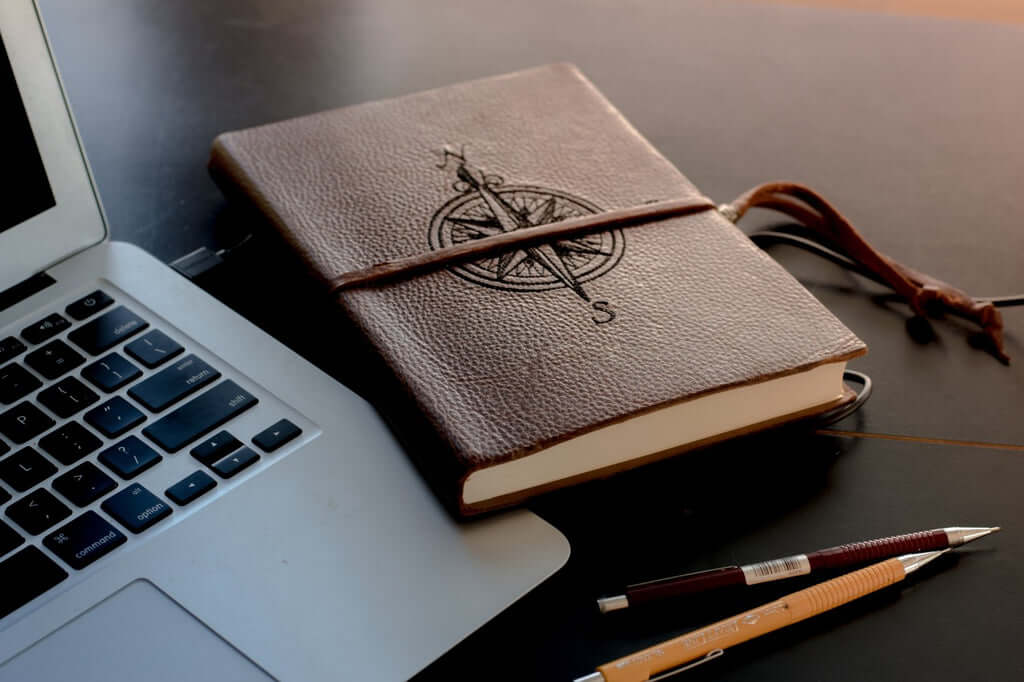 A journal and a laptop and other desk-related miscellany