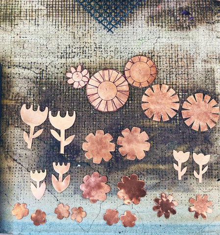 Copper sheet cut in the shape of flowers to be enameled in bright colors in the kiln.