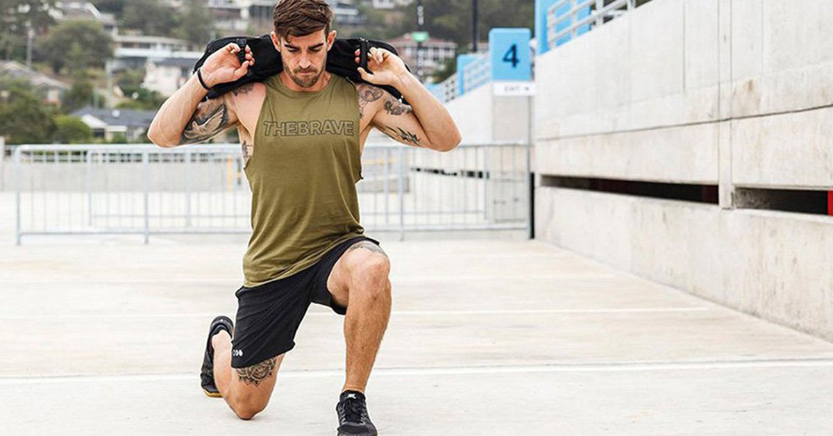 athlete doing lunges with sandbag