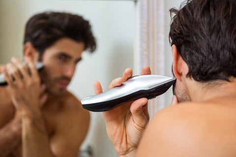 man trimming his beard in the mirror