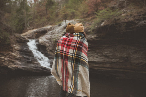 Couple cuddling under layers while camping