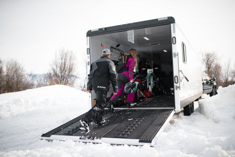 Husband and wife walking into snowmobile trailer