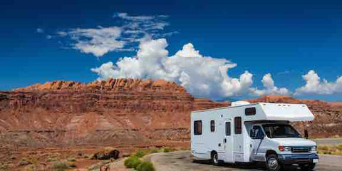 Rv driving on the road through the desert surrounded by red rocks