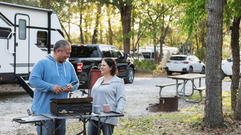 a man and a woman grilling out side an RV