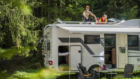 man and woman sitting on the roof of an RV