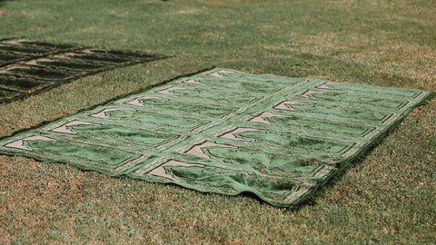 A green rug placed on the grass