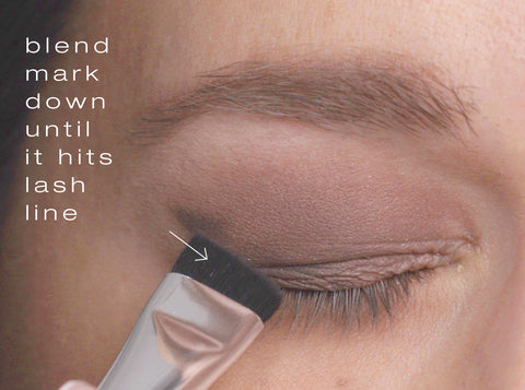 Model using the angled brush to blend the v shaped mark down until it hits the lash line