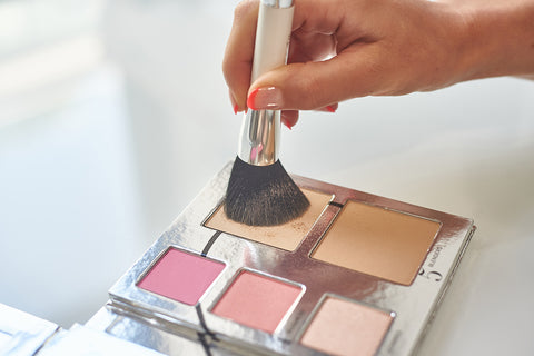 Model dipping makeup brush into the Fold Out Face Palette