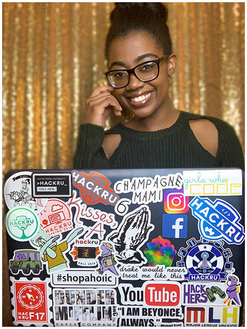 Joyce Van Drost headshot sitting behind a laptop decorated with stickers