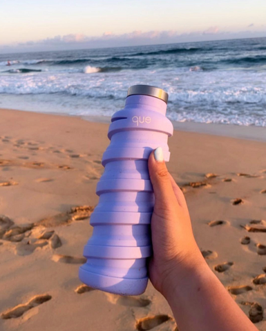 Que's Collapsible Water Bottle in front of the Ocean