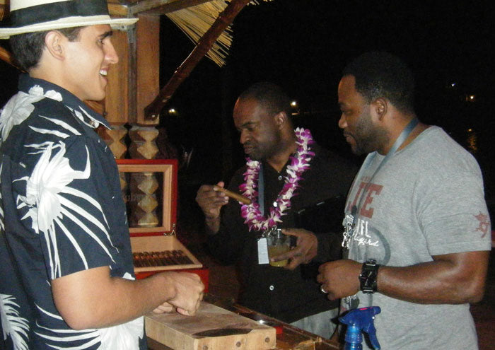 Two gentlemen carefully examining their cigars before lighting up.