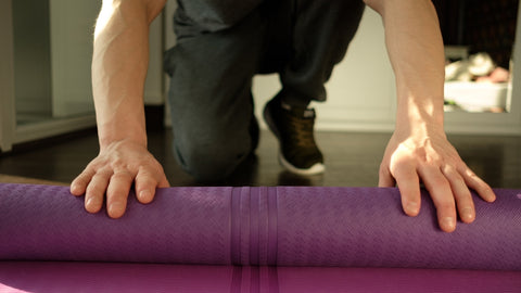 man rolling a yoga mat
