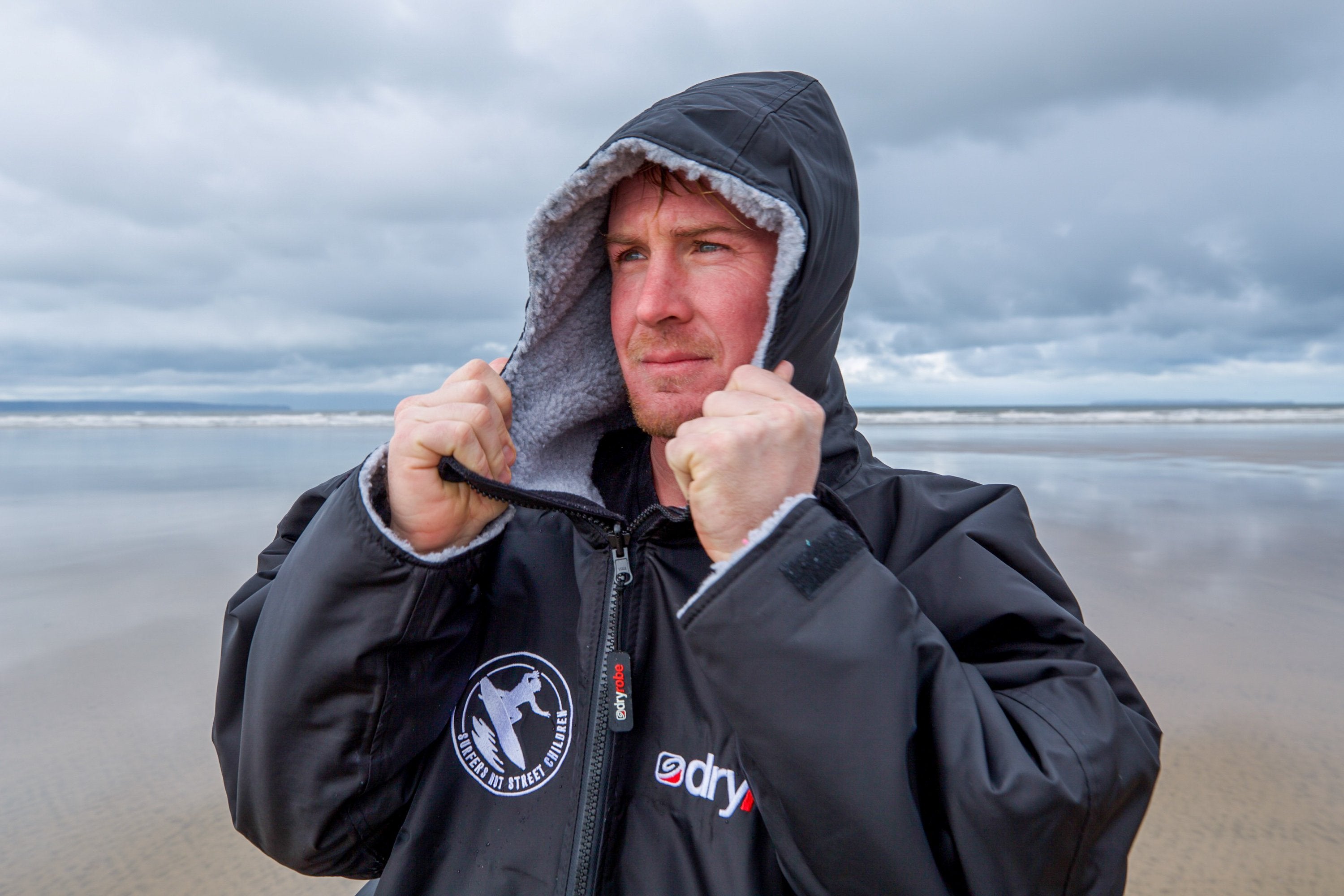 Big wave surfer Andrew Cotton modelling the official Surfers Not Street Children dryrobe 