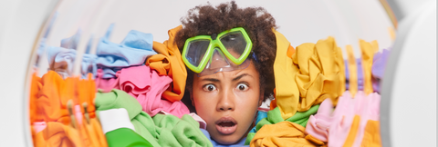 Overloaded Washer Machine with Colorful Clothes and a Woman looking Worried