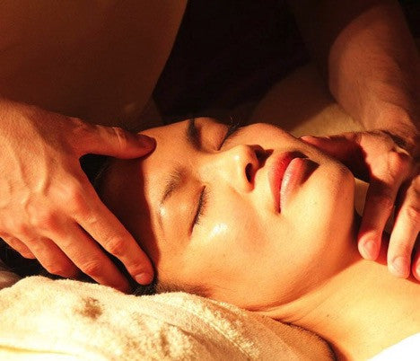 A woman with a relaxing expression receives a facial massage.