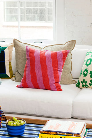 coussin rayé rouge et rose posé sur un canapé blanc