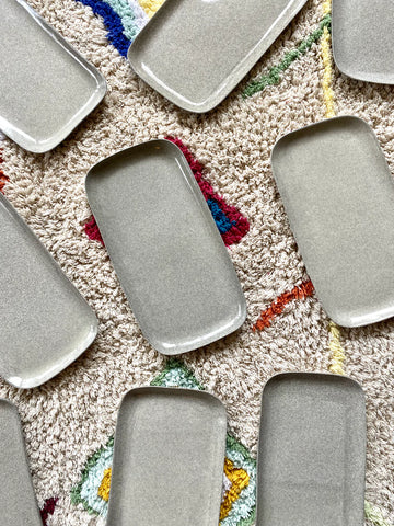 assiettes en céramique grises rectangulaire pour sushis sur tapis blanc aux motifs multicolores