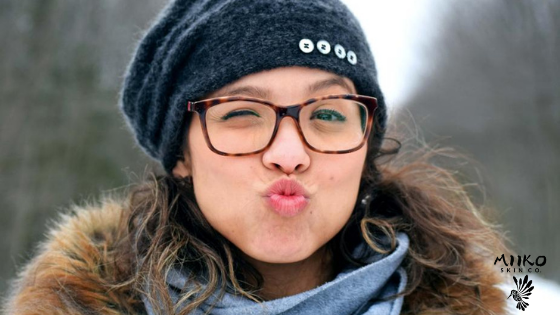 person wearing a hat outside in the snow winking at the camera