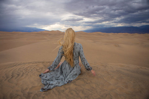 Astrobandit wearing Dreamers and Drifters grey wrap dress sitting on the sand