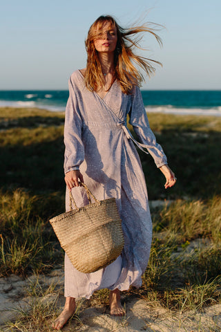 soft grey wrap dress model holding seagrass bag