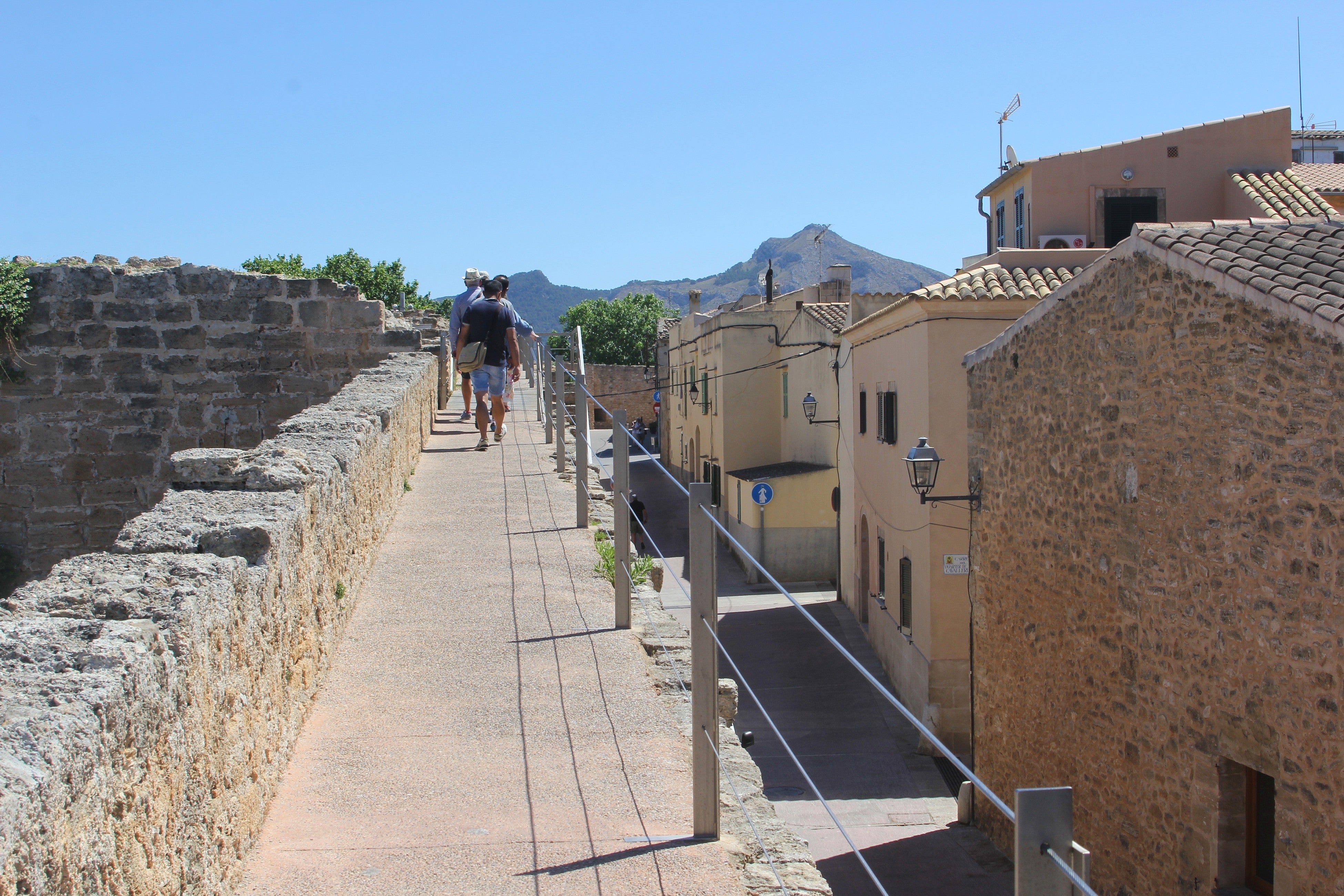2. Explore the Alcúdia Walls - Tourists walk on the ancient city walls in Alcudia, Mallorca, Spain