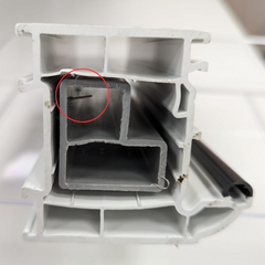 Using a pin to fix a thermal insert in a PVC window frame