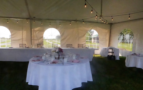 wedding tent set up with tables, chairs  and white linens