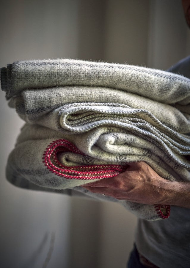 holding a stack of 100 percent british wool throws and blankets by The British Blanket Company