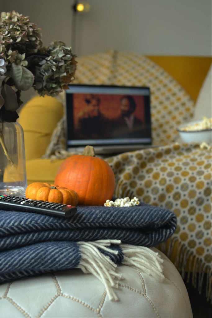 cosy living room movie night with wool blankets and popcorn on a yellow sofa