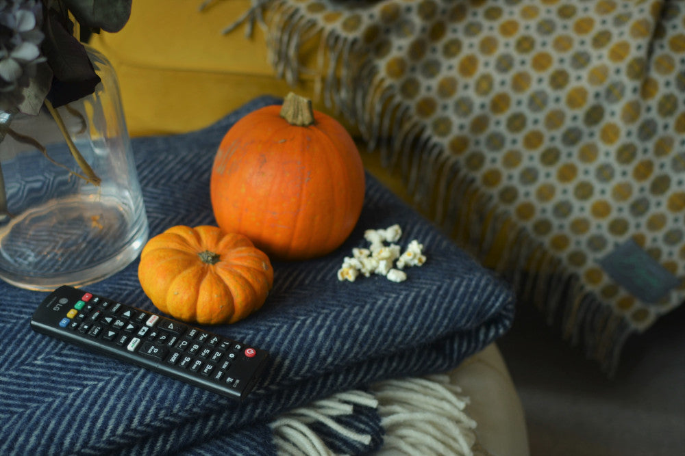 cosy living room with blue wool herringbone blanket and yellow spotty blanket pumpkins and popcorn