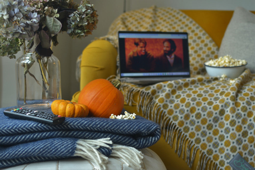 cosy autumn movie night with wool blankets pumpkins and popcorn on a yellow sofa