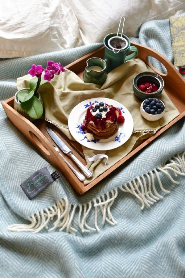 breakfast in bed scene with tray of pancakes and light blue wool blanket