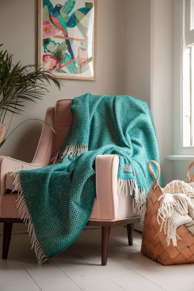 Teal blanket draped over a pink pastel armchair