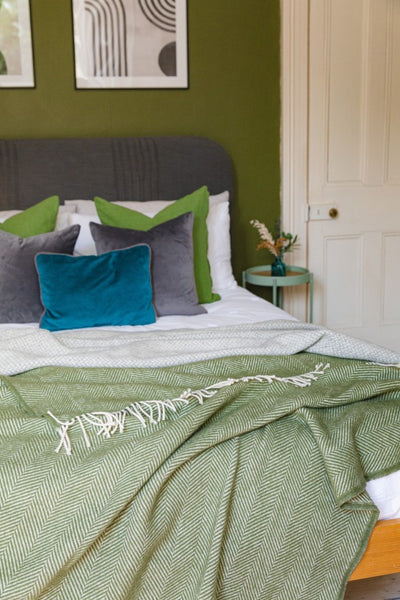 Green wool blanket draped on a double bed