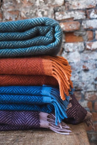 Stack of colourful woven wool blankets on a wooden bench