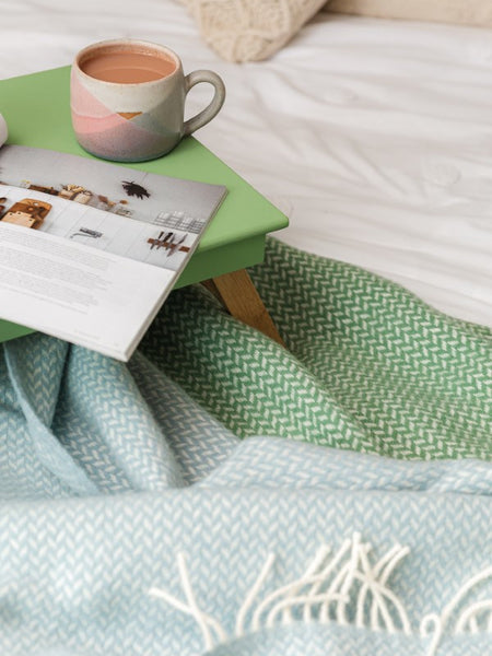 cosy breakfast in bed tray with light blue and green wool blankets and tea in a handmade mug