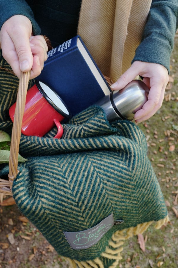 autumn picnic basket with green wool blanket thermos flask and red mug