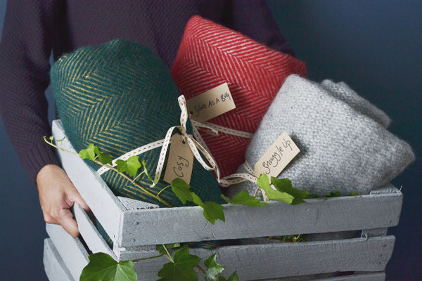 Green red and grey wool blankets with cosy labels in a box for Christmas