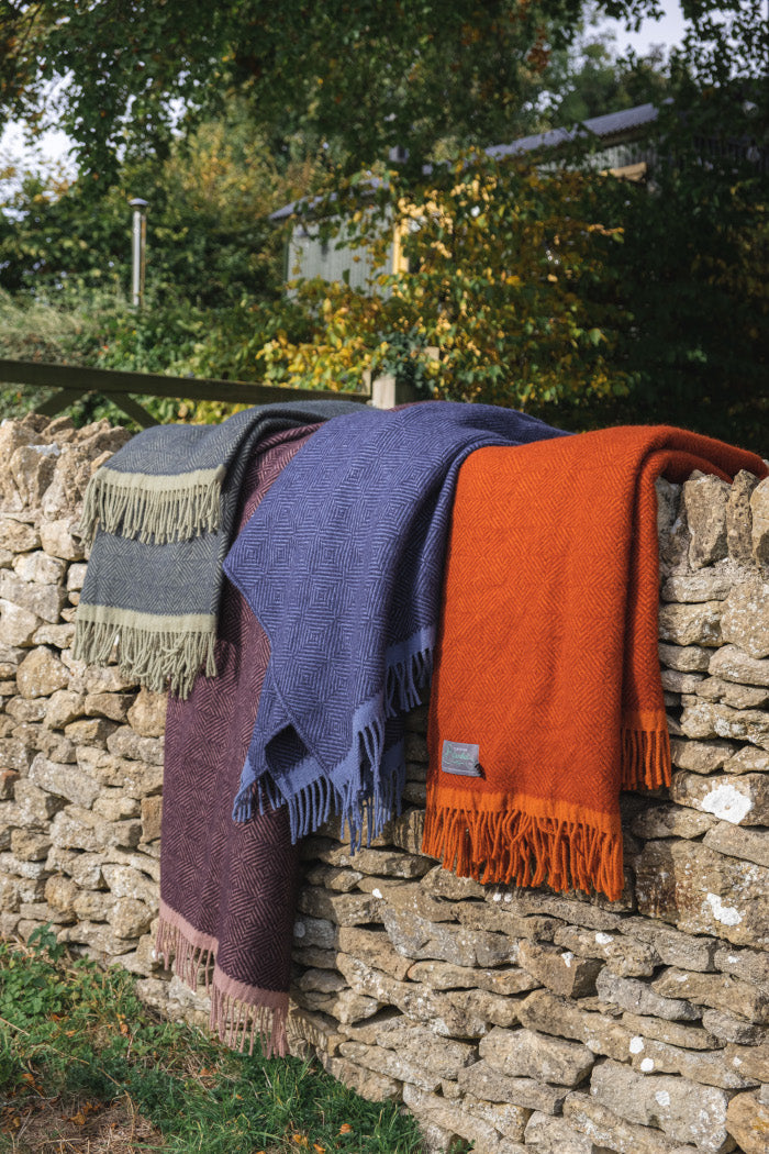 The British Blanket Company four autumn colour wool blankets from Wildweave collection on a stone wall