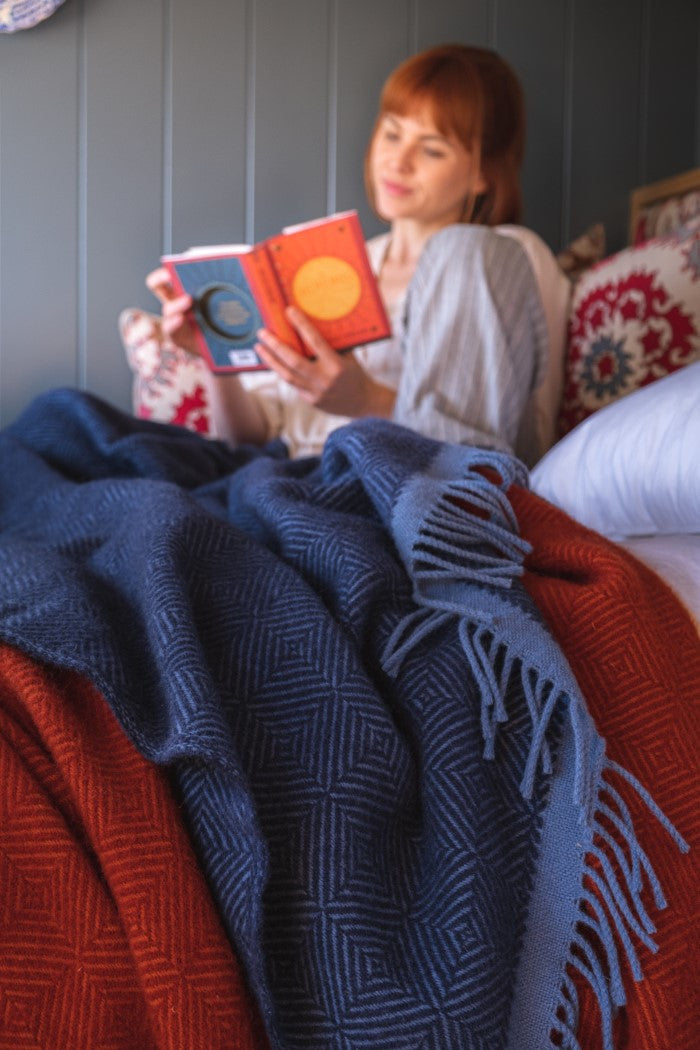 The British Blanket Company wildweave wool blankets blue and rust red on a bed