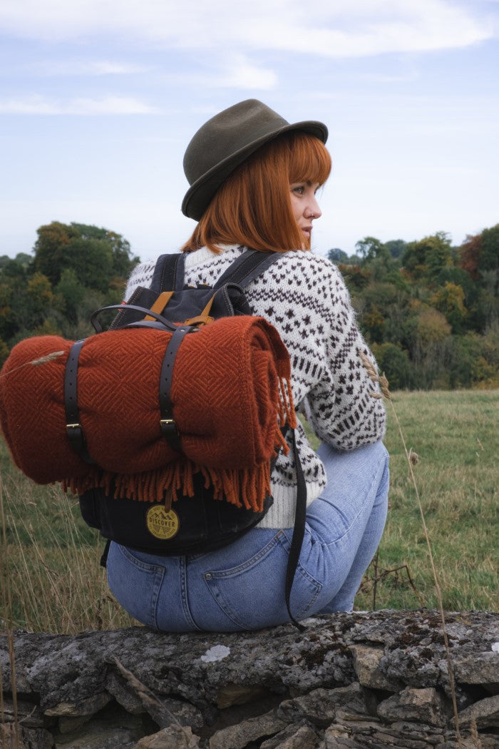 The British Blanket Company wildweave red red blanket rolled on a rucksack for autumn walk