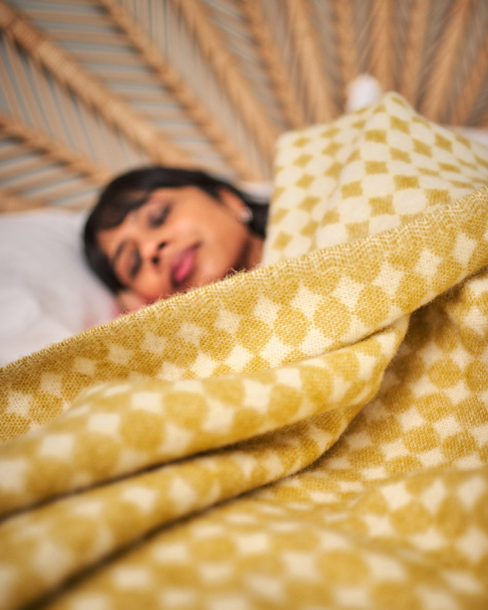 sleeping woman comfortable and warm in bed under a yellow wool blanket from The British Blanket Company