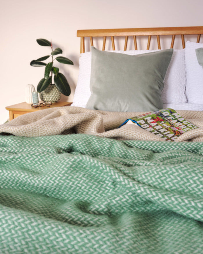 fresh bedroom decor with sage green and beige wool blanket throws on a wooden bed