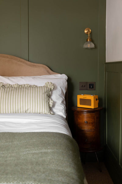 bed with a green blanket and a yellow radio